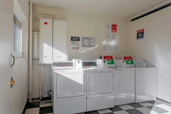 A white room with a black and white checkered floor and a white refrigerator.